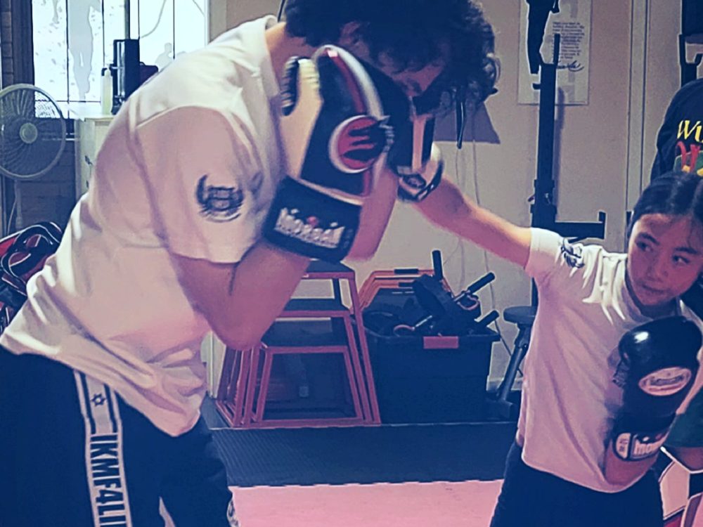 Kids & Juniors Krav Maga: a junior student punching pads with her instructor at Close Combat